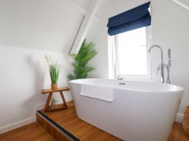 A bathroom with a freestanding tub and a plant at 5 St Gwithian Apartments