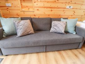 A grey fabric sofa with four cushions in a wooden room at Mallard View in Cockerham near Lancaster
