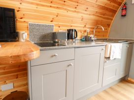 A kitchen with grey cabinets wooden wall paneling a microwave kettle toaster and a sink at Mallard View in Cockerham near Lancaster