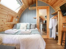 A bedroom with a bed with pillows robes hanging on a rack and a mirror door at Mallard View in Cockerham near Lancaster
