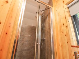 A shower with glass doors and a metal showerhead in a bathroom with wooden walls at Mallard View in Cockerham near Lancaster