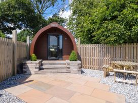 A wooden pod with glass doors on a paved patio with wooden fence and picnic table at Mallard View in Cockerham near Lancaster