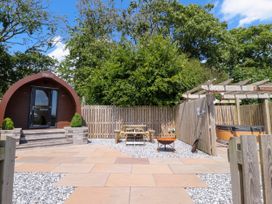 A wooden pod with steps a picnic table a fire pit a hot tub under a pergola and a fenced garden area at Mallard View in Cockerham near Lancaster