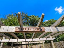 A wooden pergola structure with a sign that reads Mallard View surrounded by trees and a blue sky at Mallard View in Cockerham near Lancaster