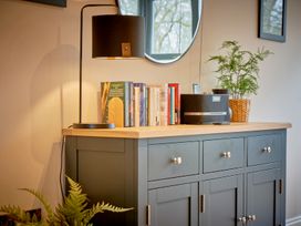 A living room with a lamp and books on a cabinet at Riverside Park 3 in Keswick