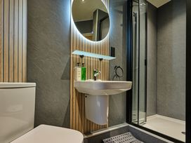 A bathroom featuring a toilet, sink, mirror, and shower at Riverside Park 5 in Keswick