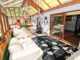 A conservatory with seating and a stove at The Woodlands Lower Level Stepaside