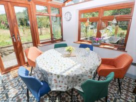 A conservatory with a round table and chairs at The Woodlands Lower Level in Stepaside
