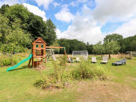An outdoor area with a playhouse, swing set, and lawn chairs at The Woodlands Lower Level in Stepaside