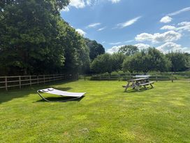 A grassy fenced outdoor area with a hammock and picnic table with a ping pong net