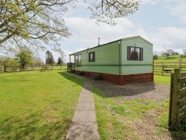 A green mobile home with a pathway leading to it and a picnic table in a grassy yard at Row End farm in Brough