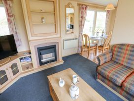A living room with a fireplace television sofa coffee table and dining table with chairs at Row End farm in Brough