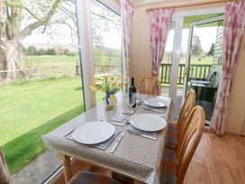 A dining table with plates glasses and flowers next to large windows and glass doors at Row End farm in Brough
