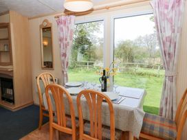 A dining area with a table set for four near large windows showing a garden at Row End farm in Brough