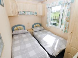 A bedroom with two single beds bedside table cabinets and a window with curtains at Row End farm in Brough