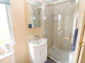 A bathroom with a shower enclosure a white sink with cabinet a mirror and a toilet at Row End farm in Brough