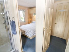 A bedroom with a bed next to a window and a bathroom with a shower seen through open doors at Row End farm in Brough