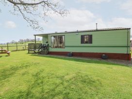 A green mobile home with a small porch and steps on a grassy lawn at Row End farm in Brough