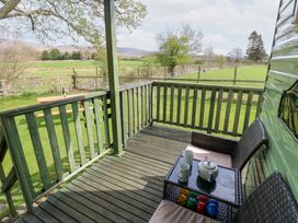 A wooden balcony with two wicker chairs a table with a teapot and cups overlooking green fields at Row End farm in Brough