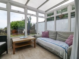 A conservatory with a sofa and table at Bryn Awel in Mynytho near Abersoch