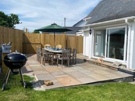 An outdoor patio with a dining table and grill at Gilfach in Abersoch