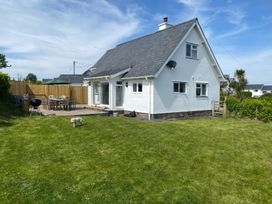 A house with a garden and deck with furniture at Gilfach Abersoch