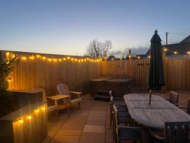 An outdoor area with a hot tub and dining table at Gilfach in Abersoch