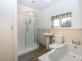 A bathroom with a shower, bathtub, sink, and toilet at Lane End Abersoch