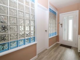 A hallway with glass brick wall and door at Nyth Y Fran Abersoch