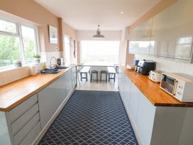 A kitchen with appliances and a dining table at Nyth Y Fran in Abersoch