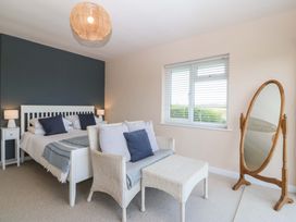 A bedroom with a bed and a mirror at Nyth Y Fran in Abersoch