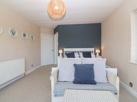 A bedroom with a bed and sofa at Nyth Y Fran in Abersoch