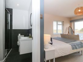 A bedroom with a bed and a bathroom visible at Nyth Y Fran in Abersoch