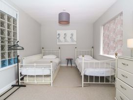 A bedroom with two beds and a cabinet at Nyth Y Fran in Abersoch