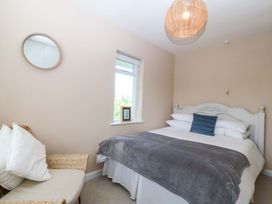 A bedroom with a bed and a chair at Nyth Y Fran in Abersoch