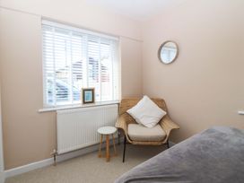 A bedroom with a chair and table at Nyth Y Fran in Abersoch