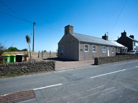 A house with a stone wall and green bins at Pen Y Sarn Sarn Bach near Abersoch