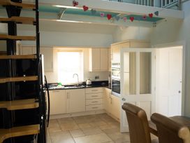A kitchen with cabinetry and a spiral staircase at Pen Y Sarn in Sarn Bach near Abersoch
