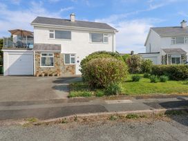 A two story house with a driveway and garage next to a garden with bushes at Swn Y Wylan in Bwlchtocyn near Abersoch