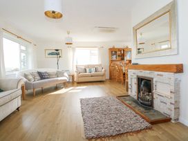 A living room with sofas a fireplace a wooden dining table and chairs and a large wall mirror at Swn Y Wylan in Bwlchtocyn near Abersoch