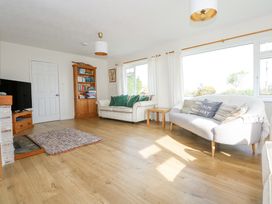 A living room with two sofas a wooden bookshelf a television and large windows at Swn Y Wylan in Bwlchtocyn near Abersoch