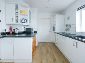 A kitchen with white cabinets black countertops a microwave kettle fire extinguisher and cooking utensils at Swn Y Wylan in Bwlchtocyn near Abersoch