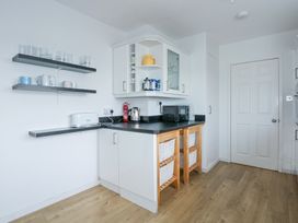 A kitchen corner with shelves holding cups and glasses a toaster kettle microwave and storage baskets at Swn Y Wylan in Bwlchtocyn near Abersoch
