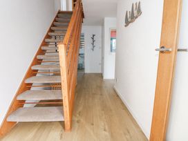 A hallway with wooden stairs carpeted steps a wooden floor a coat rack and a door at Swn Y Wylan in Bwlchtocyn near Abersoch
