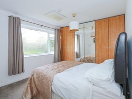 A bedroom with a bed an orange bedspread a wardrobe with mirrored doors and a window with curtains at Swn Y Wylan Bwlchtocyn near Abersoch