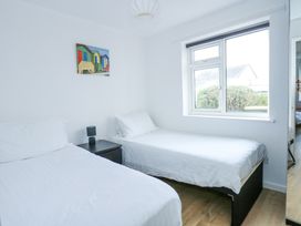 A bedroom with two single beds a black nightstand with a lamp and a window overlooking bushes at Swn Y Wylan Bwlchtocyn near Abersoch