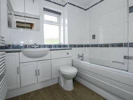 A bathroom with a sink, toilet, bathtub, mirrored cabinet, and window at Swn Y Wylan in Bwlchtocyn near Abersoch