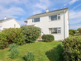 A two-story white house with bushes and grass in front under a blue sky at Swn Y Wylan in Bwlchtocyn near Abersoch