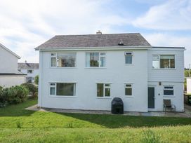 The back view of a two story white house with multiple windows a door a chair and a grassy lawn at Swn Y Wylan in Bwlchtocyn near Abersoch