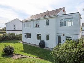 A white two-story house with multiple windows and a grass yard with bushes at Swn Y Wylan Bwlchtocyn near Abersoch